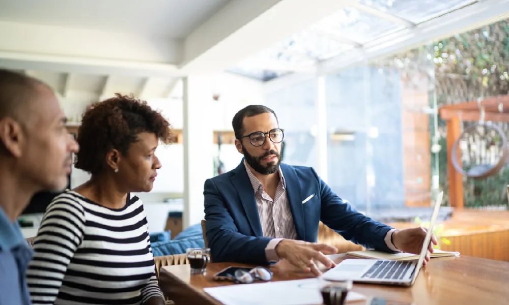 A couple goes over their money situation with a financial advisor on a laptop.