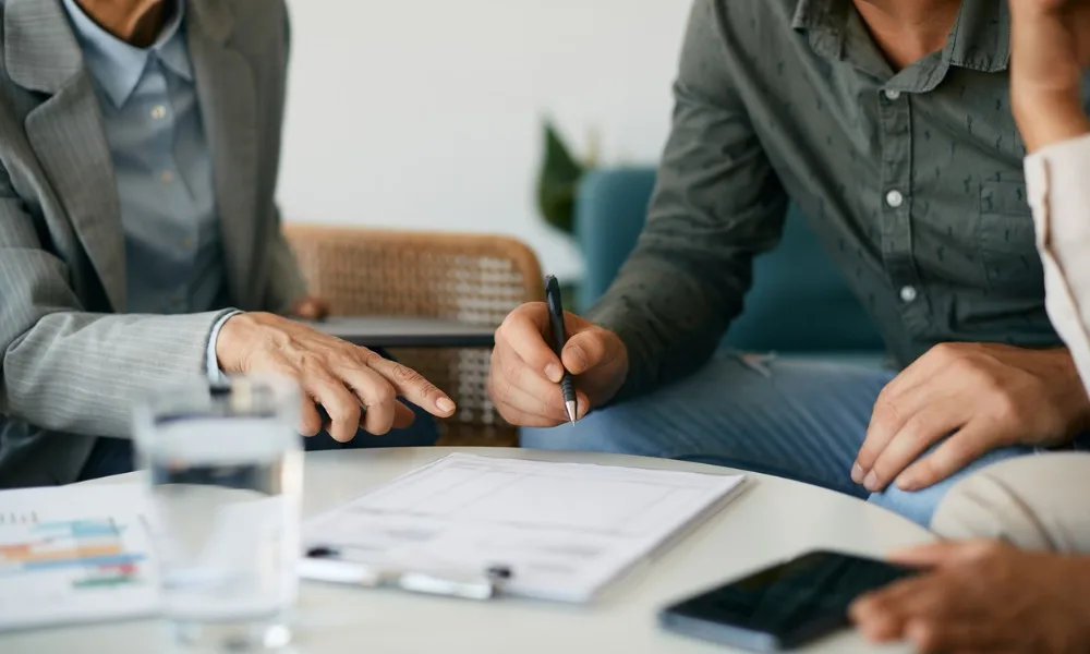 A couple signing a life insurance contract with an agent explaining reasons life insurance won’t pay out.
