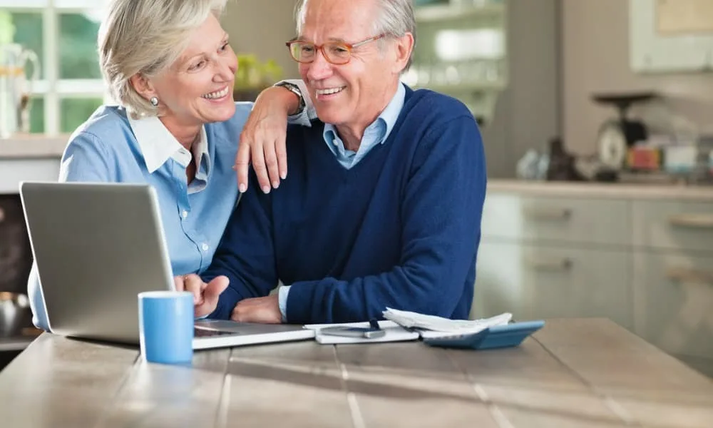 An elderly couple smiling after finding a realistic retirement calculator.