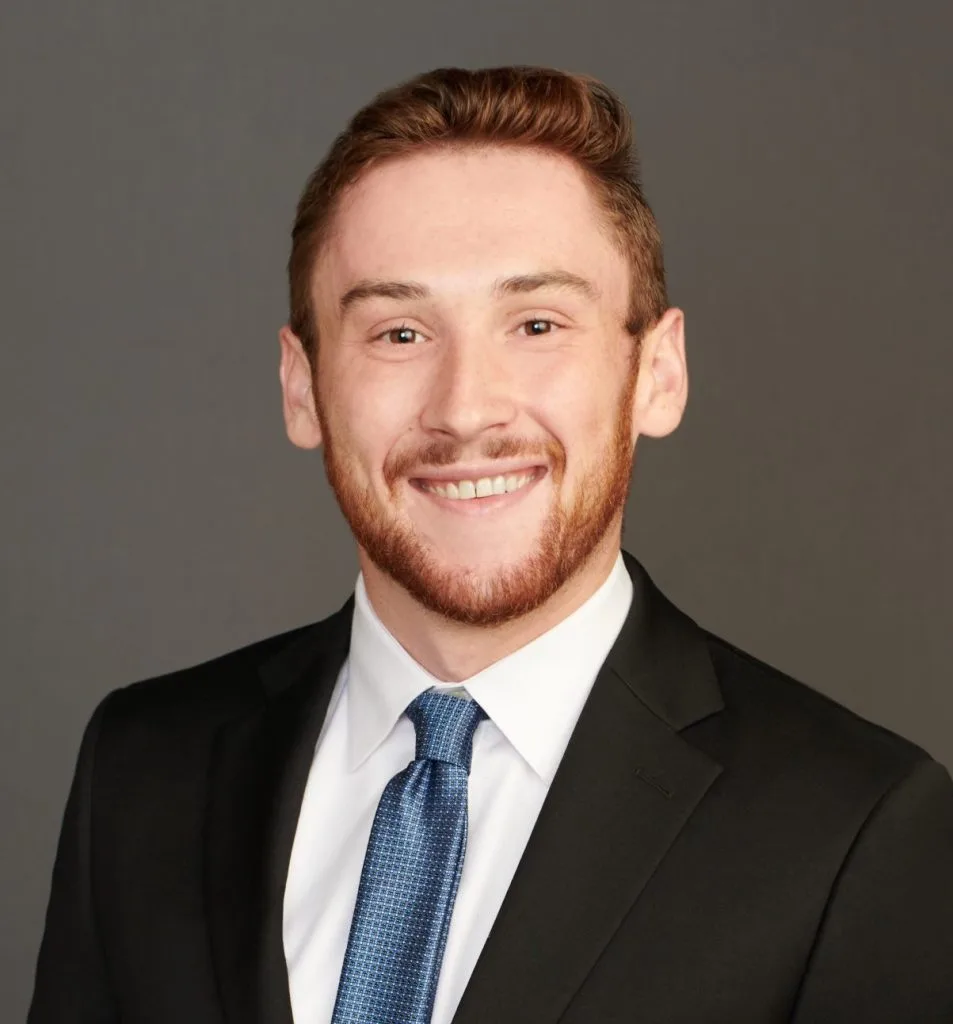 Man in a suit with a blue tie smiling against a plain background, related to AGT – Portfolio Management.