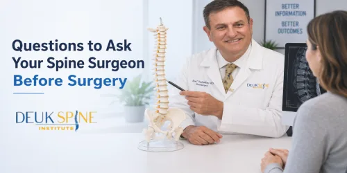 Doctor explaining spine surgery to a patient using a spine model in a medical office.