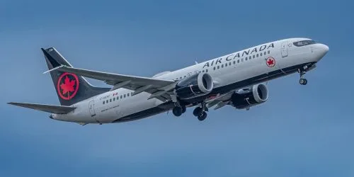 Air Canada airplane flying against a cloudy sky.
