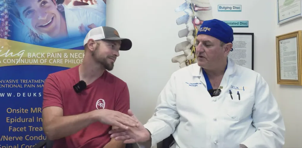 Man in a red shirt and a doctor in a white coat shake hands in a medical office.