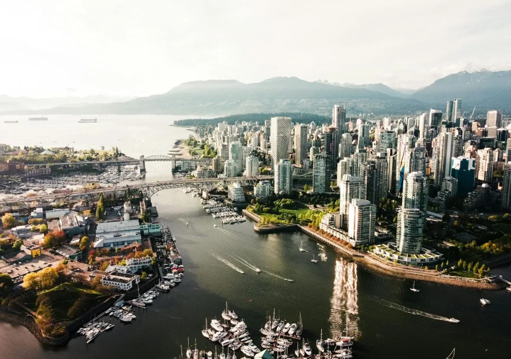 Aerial view of a city skyline with tall buildings, bridges, and boats in a harbor.