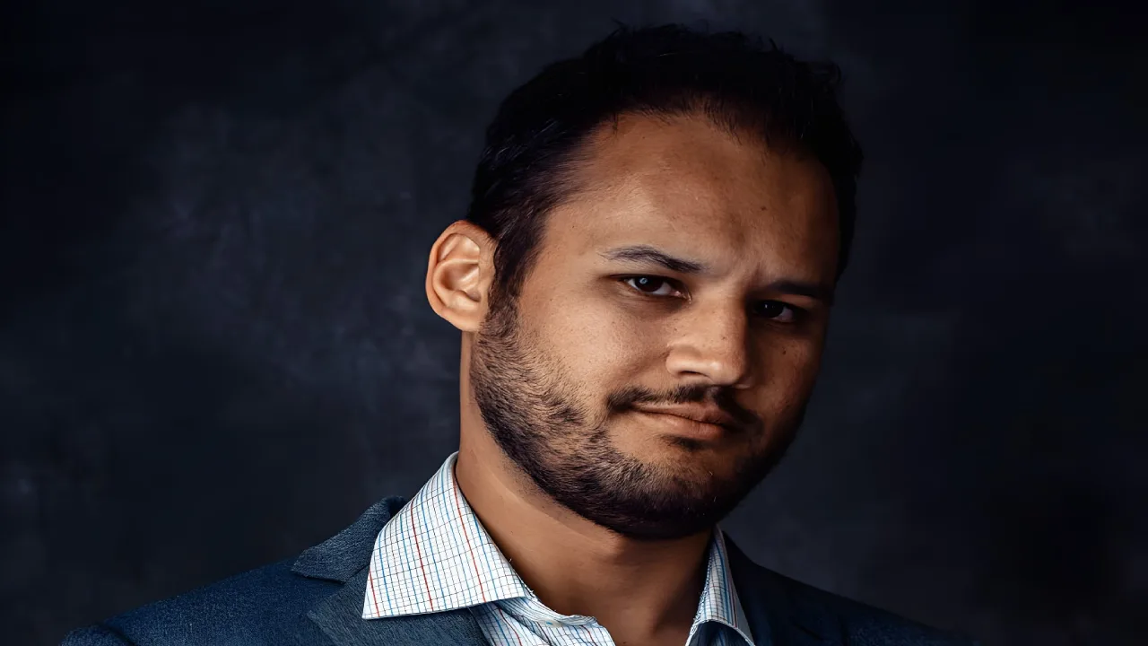 Man with a beard wearing a suit jacket and checkered shirt.