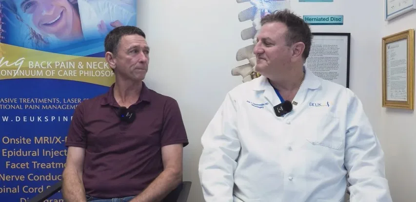 A doctor in a white coat talks with a patient in a medical office.