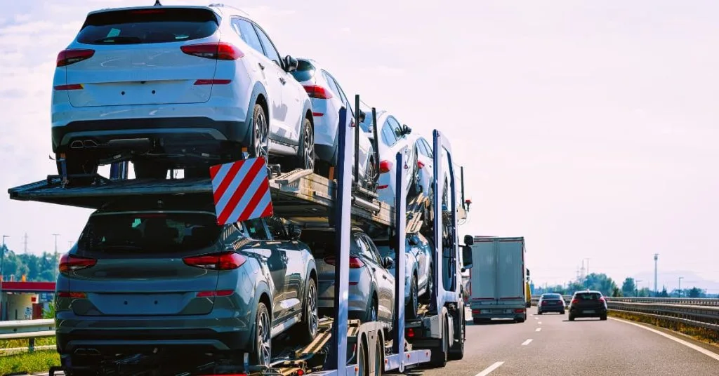 Car Shipping Guide: How to Choose Carriers & Transport Safely 3 Loaded car hauler trailer transporting multiple SUVs on an open highway, part of long-distance vehicle transport or dealership delivery fleet