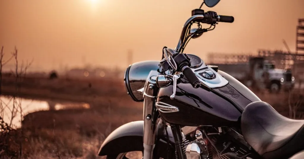 Ultimate Motorcycle Towing in Maryland: Get Help Now 1 Close-up of a Harley-Davidson motorcycle parked near a rural road at sunset, symbolizing a roadside breakdown and the need for towing assistance.