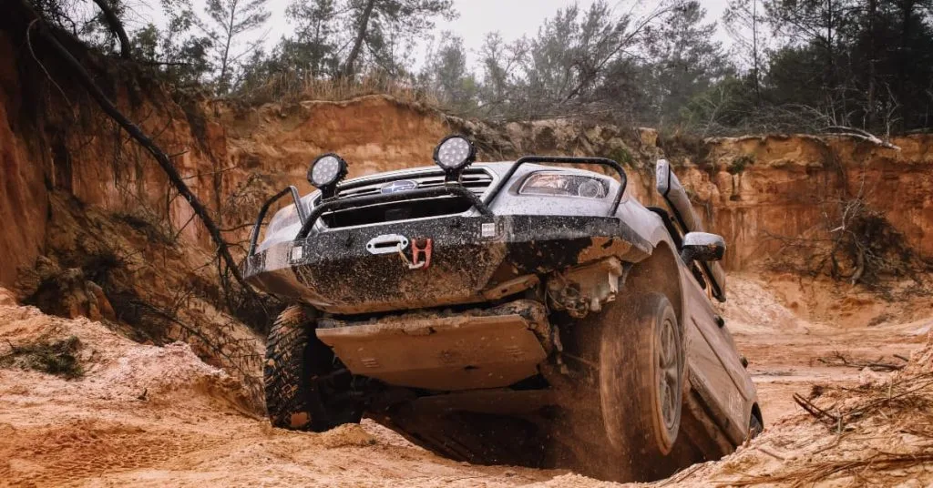 Off-Road Recovery in Maryland: Expert Vehicle Rescue Services 3 Off-road SUV stuck at an angle on rugged, muddy terrain in a canyon-like area, showing the need for off-road recovery assistance.