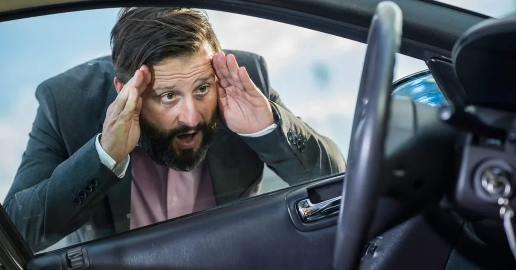 Car locked Out in Frederick: Your Complete Guide to Emergency Lockout Solutions 2 Stressed man in a suit looking through a car window with hands on his head, realizing he is locked out of his vehicle with the keys inside.