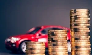A car parked behind a series of increasingly high coin piles