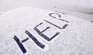 The word “Help!” written into the snow on top of a car.