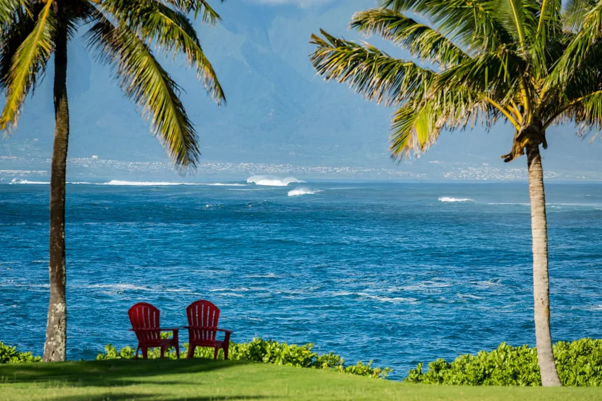 Maui Real Estate Market Update Q4 2024 Vol. 2 1 Two chairs along the Shoreline on Kuau Point looking at big breaking waves on the outer reefs of Maui's North Shore