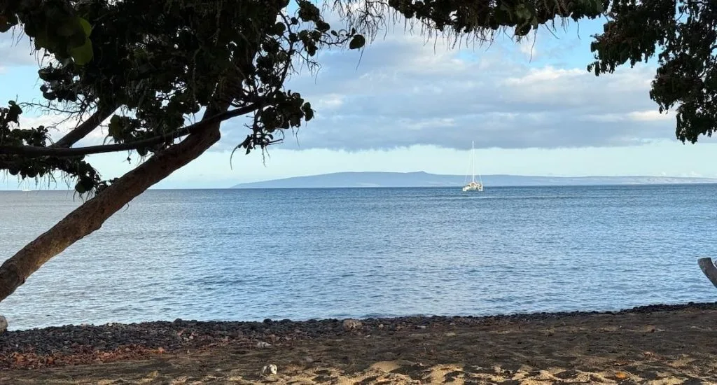 Maui Real Estate Market Update Q2 2025 Vol. 2 Cover Photo. A shot taken from the beach at Olowalu with a sailboat and Kaho'olawe in the distance.