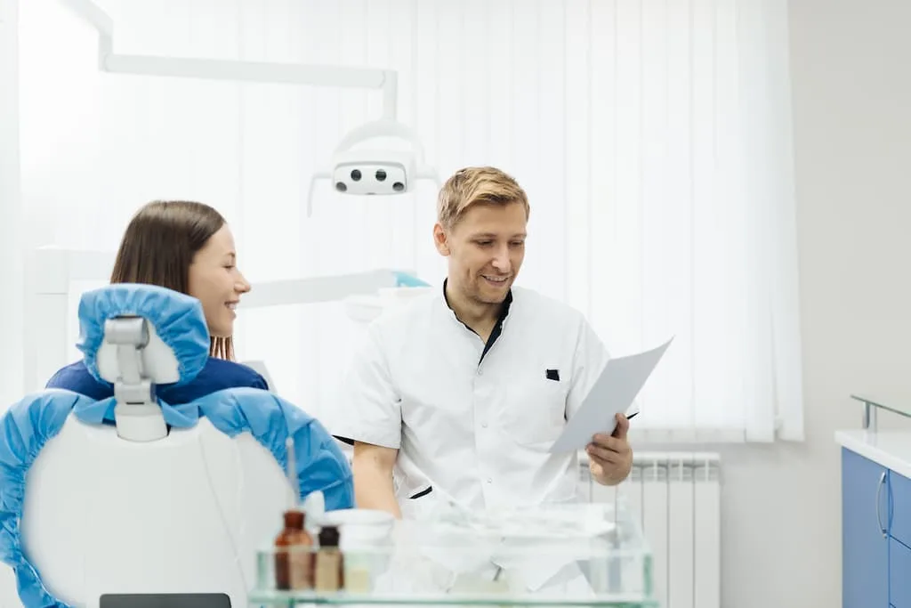 gum disease treatment options: deep cleaning vs. surgery 4 a dentist discusses paperwork with a patient in a dental office.