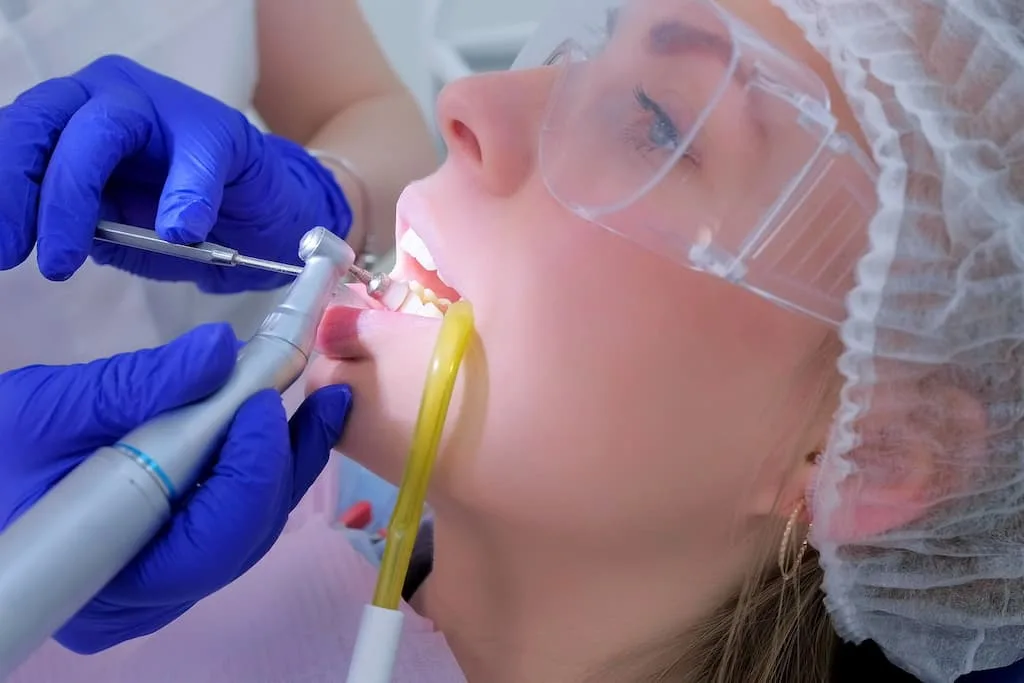 gum disease treatment options: deep cleaning vs. surgery 3 a dentist performs a dental procedure on a patient wearing protective eyewear.