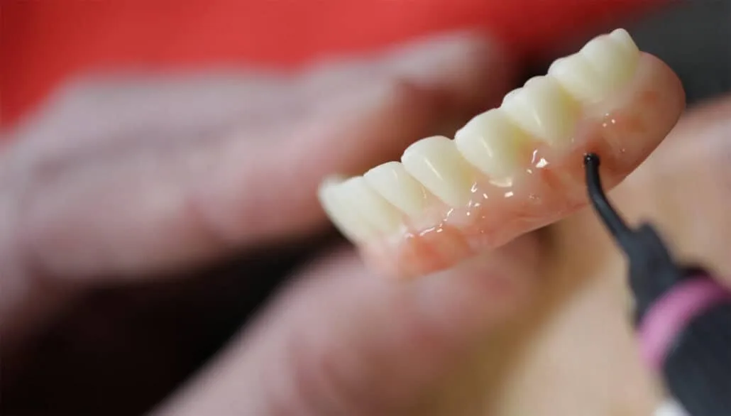 endodontist using a tool on synthetic gums and teeth.