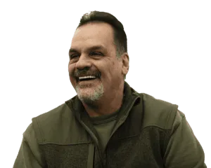 a middle-aged man wearing an olive-colored jacket and shirt, smiling.