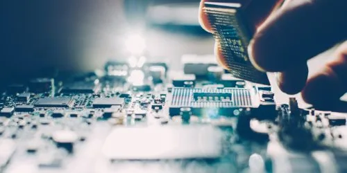 Close-up of a person installing a CPU on a circuit board, showcasing technology and precision in electronics assembly.