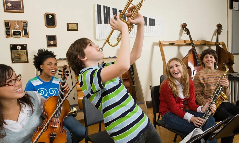 Five students have fun playing beginner instruments in a band.