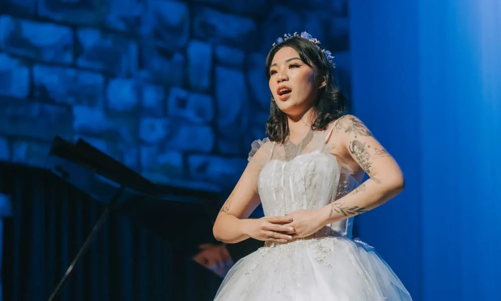 Belt It Out, Baby! 10 Tips to Singing with Power 9 Female opera singer singing with her hand on her stomach to feel the breath in her abdomen, demonstrating how to sing with power.
