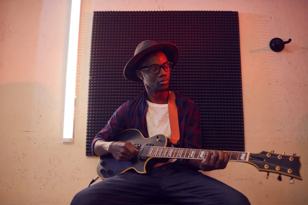 artist playing guitar wearing a hat