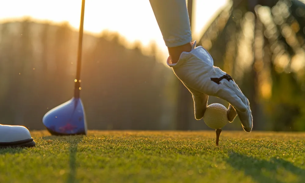 Someone placing a golf ball on a tee
