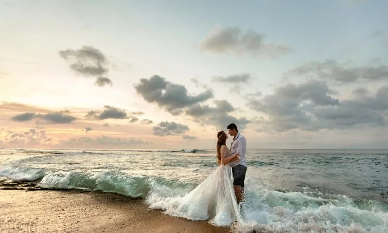 A couple embraces as waves wash over their feet during a Rehoboth Beach wedding.