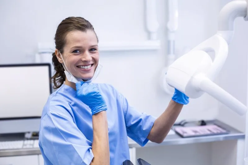 Portrait of smiling dental assistant adjusting light in dental clinic