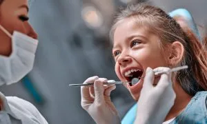 A picture depicting a young girl at the dentist for her dental examination.